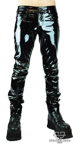 a man wearing shiny black pants and black boots.  the pants are very tight fitting and have a highgloss finish. the boots are laceup and have a chunky platform sole. the man is standing with his legs together, and he is looking down. the background is a white wall.  the man is wearing this outfit as a part of a fashion photoshoot.