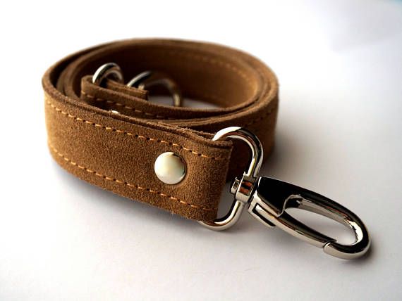 a closeup image of a brown suede shoulder strap with silver hardware. the strap is folded in half and the silver hook is visible.  the strap appears to be handmade and has a vintage aesthetic.