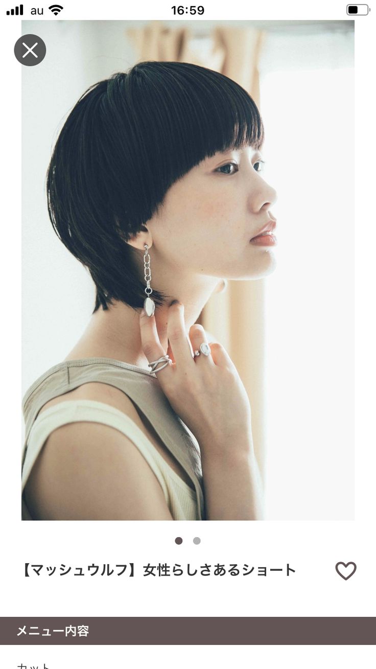 a young woman with short, black hair is wearing a tank top, earrings, and a ring. she is looking to the right, and her face is slightly tilted upward. the background is out of focus, suggesting a simple, clean aesthetic. the image is welllit and focuses on the model's face and jewelry.