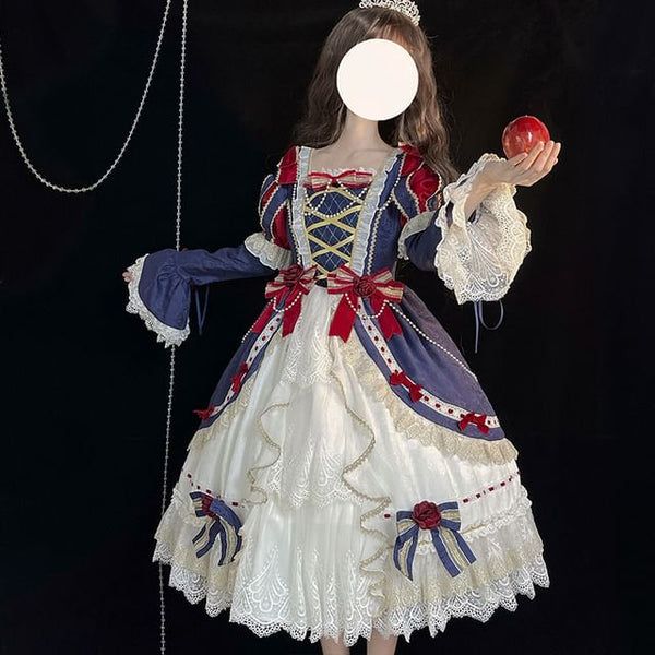 a woman is wearing a snow white themed lolita fashion dress. the dress is predominantly white and navy blue, with red and gold accents. she is posing against a black background.