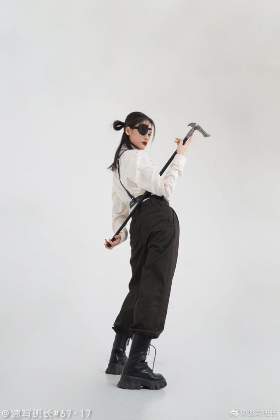 a young woman in stylish attire poses against a minimalist white background. she holds a distinctive cane, adding an element of intrigue to her look. her outfit, featuring a white top, black pants, and chunky black boots, exudes an air of effortless cool. the studio lighting accentuates her pose, creating a captivating portrait.