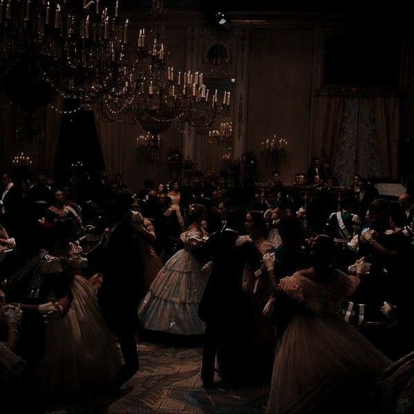 a dimly lit ballroom filled with people dancing in elegant dresses and suits. the scene is bathed in the soft glow of candlelight and the reflection of a large chandelier. the atmosphere is both grand and intimate, with couples swaying to the music in the background. the ornate architecture of the room adds to the sense of grandeur and luxury. the image evokes a sense of history and romance.