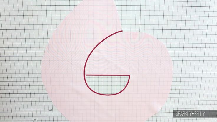 the image shows a light pink fabric with a grid pattern underneath. a drawing of a shape in maroon is on the fabric. the shape resembles the number "6" or an incomplete circle with a horizontal line. the fabric appears to be cut into two pieces. the lower right corner of the image contains the text "sparkly belly".