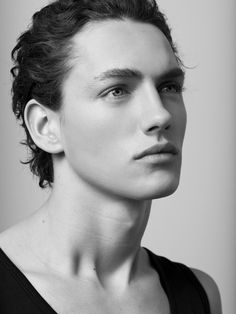 a black and white closeup portrait of a male model with slicked back hair. he is wearing a black tank top and is looking off to the side. the image has studio lighting and a shallow depth of field.