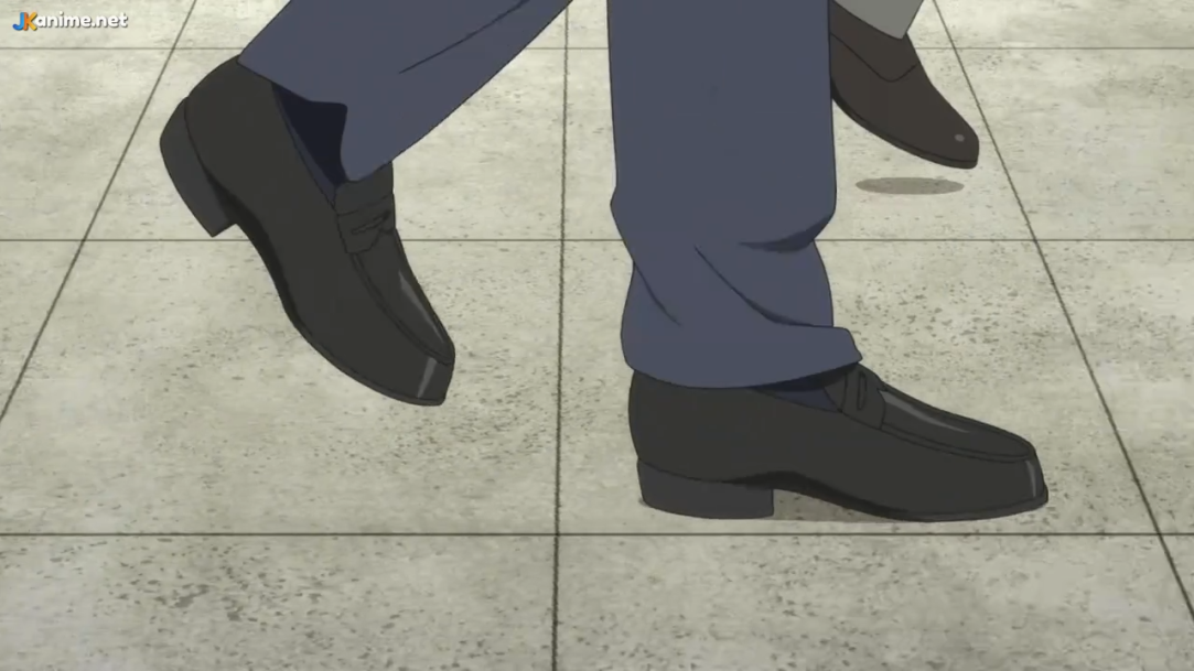 a lowangle shot of someone's legs walking on gray tile floor. they appear to be wearing dress shoes and dark blue dress pants.  the lighting is soft, casting faint shadows on the floor.