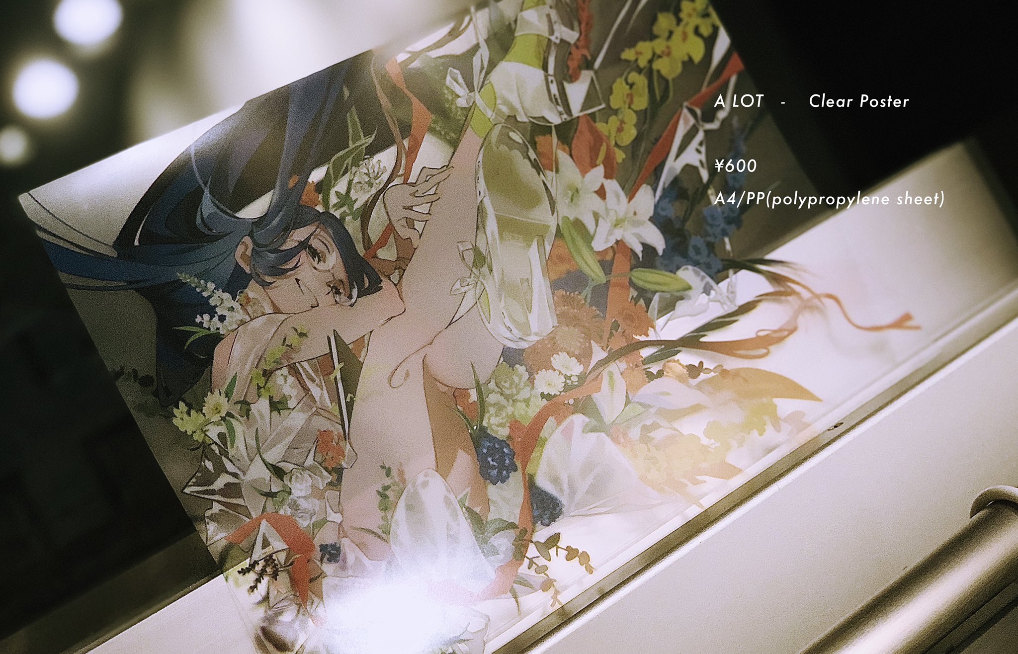 the image shows a clear poster of an anime girl lying on her side with flowers surrounding her. the poster is sitting on a white surface. the poster is titled "alot  clear poster" and costs ¥600. the poster is printed on a4/pp (polypropylene sheet).