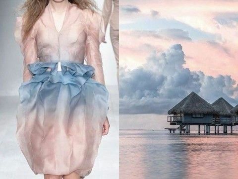 a woman is wearing a beautiful light pink and blue dress with a ruffled hem. she is standing in front of a background of a tropical paradise. the sky is a beautiful gradient of pink and blue with fluffy clouds. in the distance is a luxurious overwater bungalow in a lagoon with crystal clear turquoise water. the scene is one of peace and tranquility.