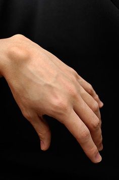 a closeup image of a person's hand and wrist against a black background. the veins on the hand are clearly visible.
