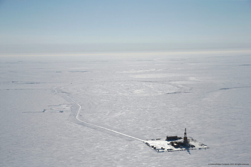 an aerial view of an oil rig in the arctic. the rig is located on a frozen sea, surrounded by snow and ice. the landscape is desolate and remote, with a long, narrow road leading up to the rig. this image highlights the challenges and environmental impacts of oil exploration in the arctic.