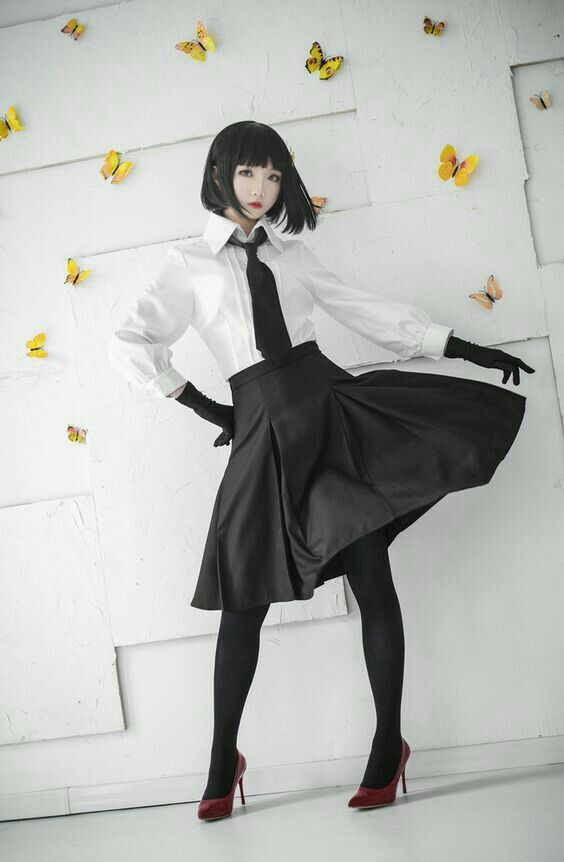a young woman is striking a pose in a studio. she is dressed in a black and white outfit that includes a white buttonup shirt, a black necktie, a black skirt, black gloves, and red high heels. she has short, straight black hair and is wearing makeup. the background is white with a textured pattern and yellow paper butterflies. the image is welllit, with the light coming from the front. the overall aesthetic of the image is stylish and playful.