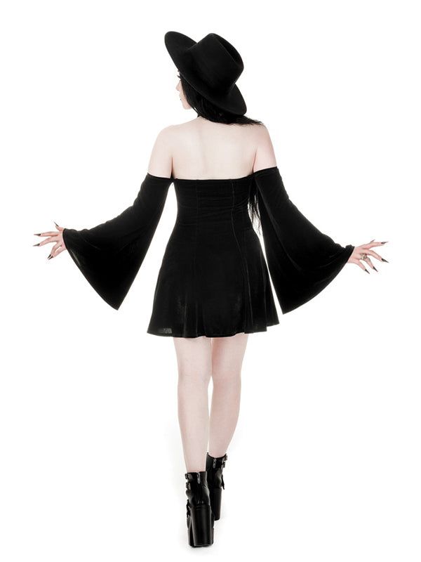 a woman wearing a black offtheshoulder dress and widebrimmed black hat. she is wearing black boots and is posing in a studio with a white background.