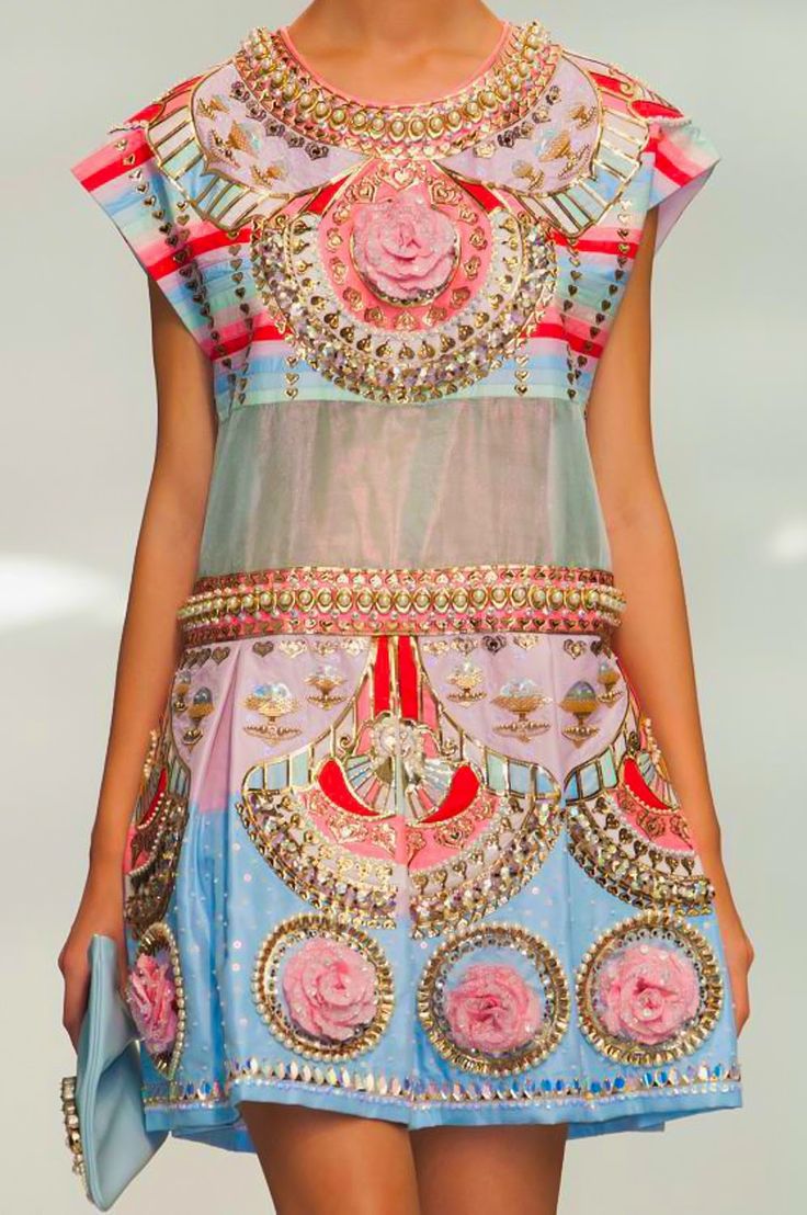 a model is showcasing a colorful and intricately designed dress. the dress features a layered skirt, a sheer top with colorful embroidery, and a beaded neckline. the design is intricate and features floral patterns, geometric shapes, and sequins. the model is posing on a runway, showcasing the elegance and glamour of the dress.  the dress is a perfect example of highfashion design.