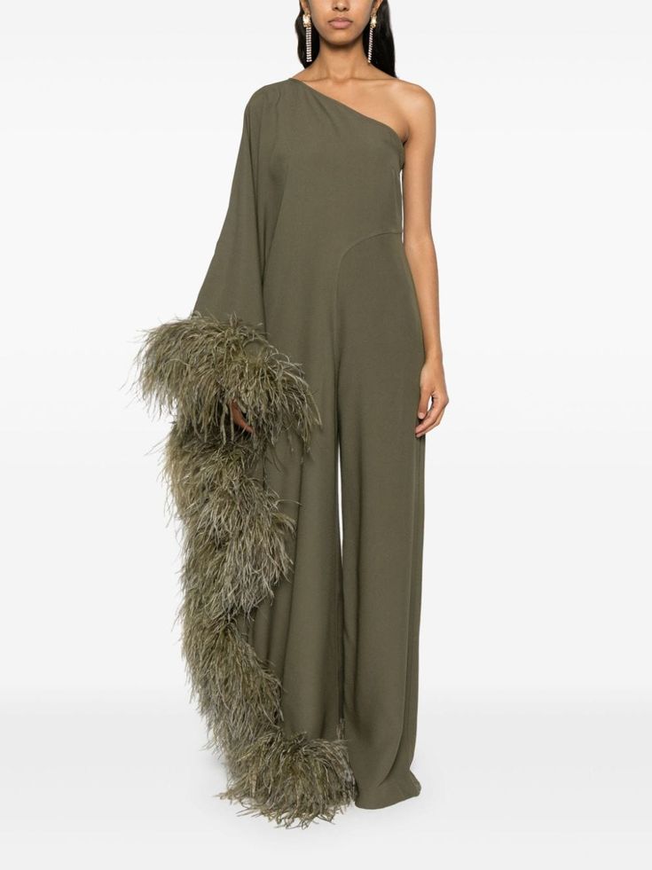 a woman model is posing in a one shoulder green dress, with a large feather trim, in a studio.