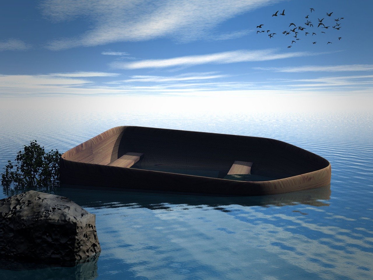 a wooden boat is adrift in the water near a rock and tree. there are birds flying in the sky. the water is calm and reflects the blue sky and clouds.