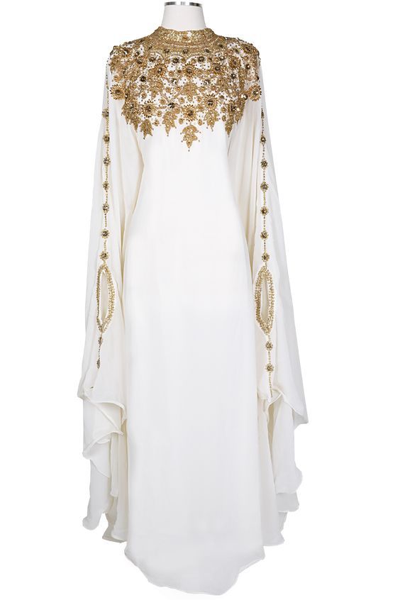 an elegant white abaya or kaftan maxi dress is displayed. the dress is made of a flowing chiffon material and features intricate gold embroidery and beading at the neckline and sleeves. the high neckline is adorned with a detailed floral pattern created with gold embellishments, which also run down the sleeves. the sleeves are long and wide with a flowing, ruffled design.  the overall look is luxurious and formal, suitable for special occasions or celebrations. the dress is presented on a mannequin against a white background.
