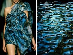 a woman is posing on a runway in a flowing blue silk dress. the dress is very intricate and detailed with many folds and ruffles. the woman is looking off to the side with a sultry expression. the background is blurred and features ripples of water. the image captures a sense of elegance and sophistication.