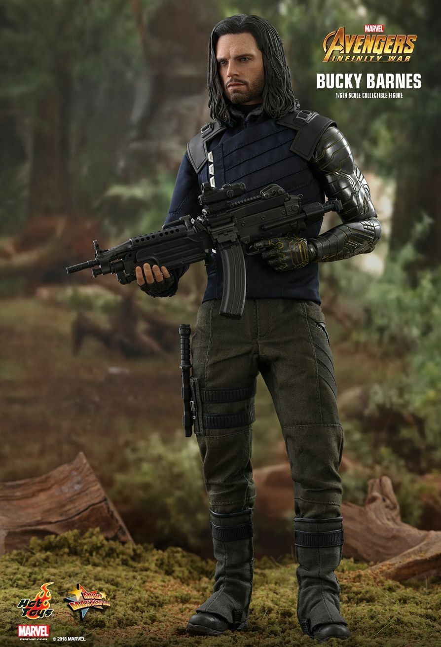 this is a promotional image of a hot toys 1/6 scale collectible figure of bucky barnes from avengers: infinity war. the figure is highly detailed and accurately depicts sebastian stan's portrayal of the character. bucky is shown holding a submachine gun, dressed in tactical gear, and standing in a forest setting.  the image is professionally lit and captures the figure's many intricate details.  the marvel and hot toys logos are visible.