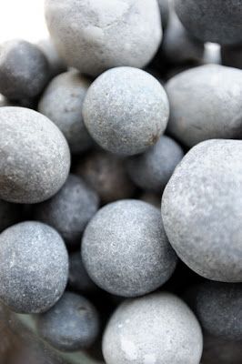 a closeup image of a pile of smooth, gray stones. the stones are round and have a soft, natural texture. they are arranged in a pile, and the image is taken from a slightly elevated angle. the background is blurred, and the stones are the focus of the image.  the image has a calming and natural feel.