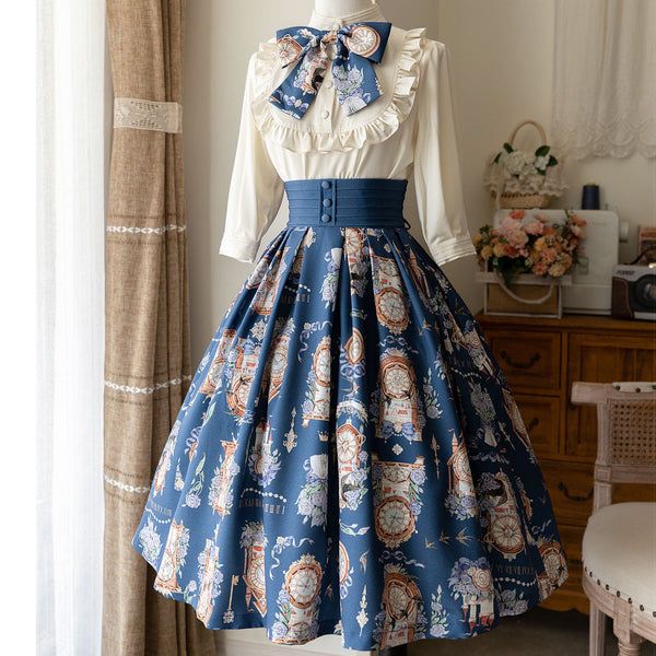a blue and white vintagestyle dress is displayed on a mannequin. the dress features a highwaisted, full skirt with a floral print of clocks and flowers. the bodice is a simple white blouse with long sleeves and a large bow at the neck. the background is a brightly lit room with a window and curtains. there is a vase of flowers on a table in the background.
