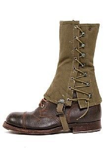 the image shows a pair of brown leather combat boots with a pair of green canvas gaiters attached. the gaiters are laced up the side and have a strap and buckle at the top. the gaiters are a common piece of military equipment that is used to protect the legs from dirt and debris.