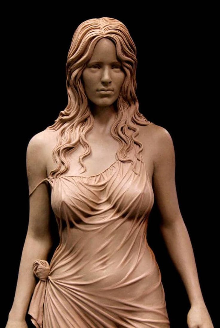 the image showcases a meticulously crafted clay sculpture of a woman. the sculpture captures the subject from the chest up, highlighting the intricate details of her flowing hair, draped clothing, and lifelike features.  the lighting is controlled, characteristic of a studio setting, and emphasizes the textures and contours of the sculpted form.
