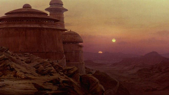 a wide shot of jabba's palace on tatooine, from star wars. the large, imposing palace is built into a rocky cliff overlooking a vast desert landscape. two suns are setting in the sky, creating a vibrant, reddishorange and purple hue. the overall atmosphere is arid and desolate, characteristic of the planet tatooine. the image captures a dramatic and iconic scene from the star wars films.