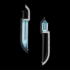 a pair of stunning earrings featuring aquamarine gemstones set in black and silver settings. the aquamarines are cut in a unique shape and are surrounded by sparkling diamonds. the earrings have a modern and geometric design that would be perfect for a special occasion.