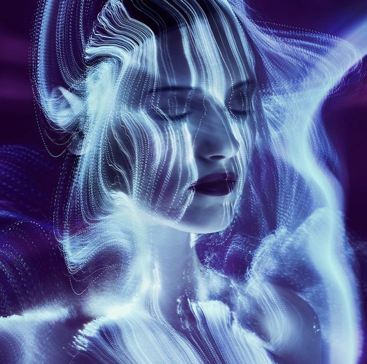 the image is a stunning example of light painting photography. a woman's face is the central focus, her eyes closed in a serene expression.  her features are subtly defined, overlaid and interwoven with streaks and swirls of luminous blue and purple light, creating an ethereal and dreamlike effect.  the light appears to flow and move, giving the impression of energy or a mystical aura. the background is dark, enhancing the luminous quality of the light that forms a veil around the woman's head and shoulders. the overall aesthetic is surreal and highly artistic, blending photographic technique with an abstract, almost digital, feel.
