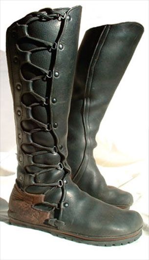 a pair of sturdy, vintagestyle leather boots stands against a neutral background. the boots, crafted from dark brown leather, reach high up the leg and feature intricate lacing and buckle details. the soles appear thick and durable, hinting at their practical use.  the overall aesthetic suggests historical footwear, potentially inspired by medieval or renaissance designs.