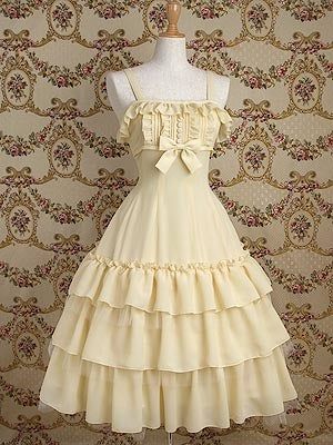 a pale yellow lolita fashion dress is shown on a mannequin in front of floral wallpaper. the dress has multiple tiers of ruffles, a square neckline, and a bow at the waist.