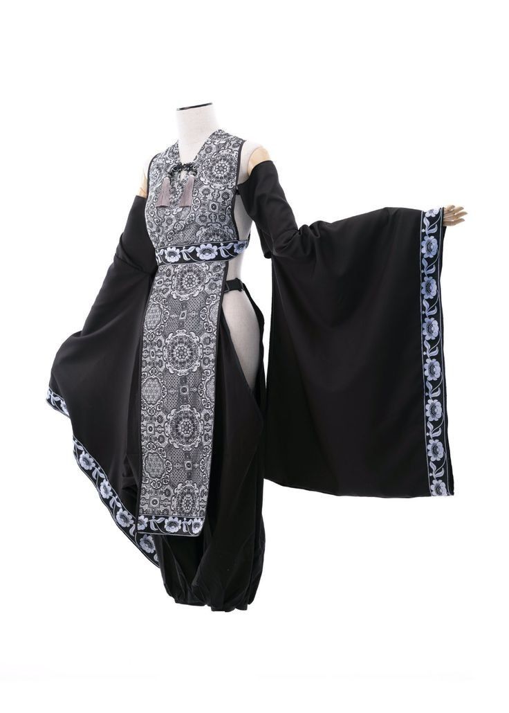 a mannequin is wearing a black and white dress. the dress has long sleeves and an intricate embroidered pattern that is predominantly floral. it looks like a very traditional costume from a foreign country.