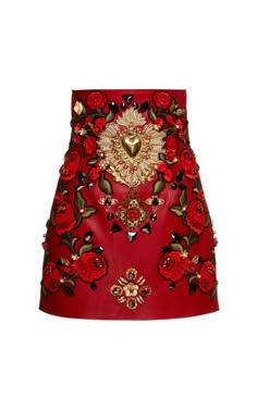 a closeup of a red embroidered skirt with a heart shape design. the skirt is made of leather and has a variety of gold embellishments. the skirt is very detailed and intricate, with a lot of work put into the design. the skirt is perfect for a special occasion or a night out.