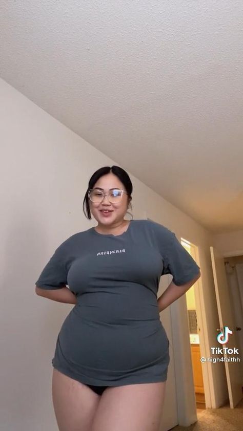 a woman wearing glasses and a grey tshirt stands in a hallway. a tiktok logo is visible in the lower right corner.