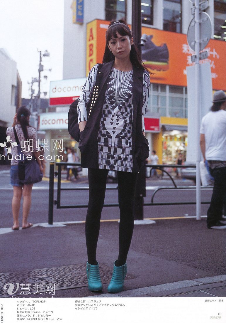 a young japanese woman poses on a city sidewalk, fashionably dressed for the camera. she sports a black and white geometric print dress, black tights, and vibrant turquoise booties. her long dark hair is styled in a high ponytail, and she carries a black shoulder bag. the urban backdrop features bustling streets, storefronts with japanese signage, and a pedestrian crossing.kw: fashion, street style, japanese fashion, urban, city life, style, clothing, outfit, portrait, posing, young woman, long hair, ponytail, dress, tights, booties, shoulder bag, sidewalk, street scene, japanese text, daytime, candid
