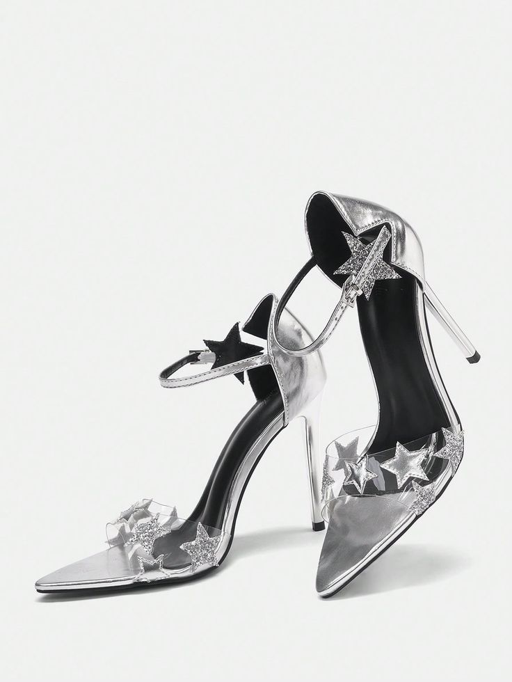 a pair of silver high heels with ankle straps and clear straps embellished with starshaped details. the heels are pointedtoe stilettos with a shiny silver finish. the shoes are positioned on a white background, with one shoe slightly angled forward.  they appear to be new and stylish.