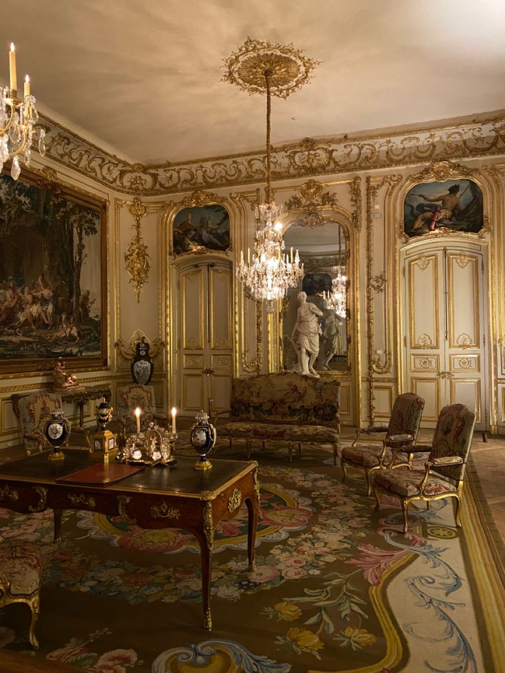 the image shows a richly decorated interior, possibly in a french palace or chateau, dating from the baroque or rococo period. the room is lavishly adorned with gold gilded woodwork, intricate moldings, and ornate details.  large tapestries hang on the walls, depicting classical scenes.  the furniture is antique, featuring finely carved wood and upholstered in luxurious fabrics. two crystal chandeliers hang from the ceiling. a large aubusson rug covers the floor. a marble statue is visible in the background. the overall effect is one of extreme opulence and elegance, reflecting a high level of craftsmanship and artistic merit. the room seems set for quiet contemplation, suggesting a private sitting room or study in a grand residence.
