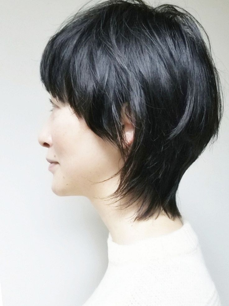 a woman with short black hair is facing to the side, wearing a white shirt. the hair is styled with a short, choppy bob.