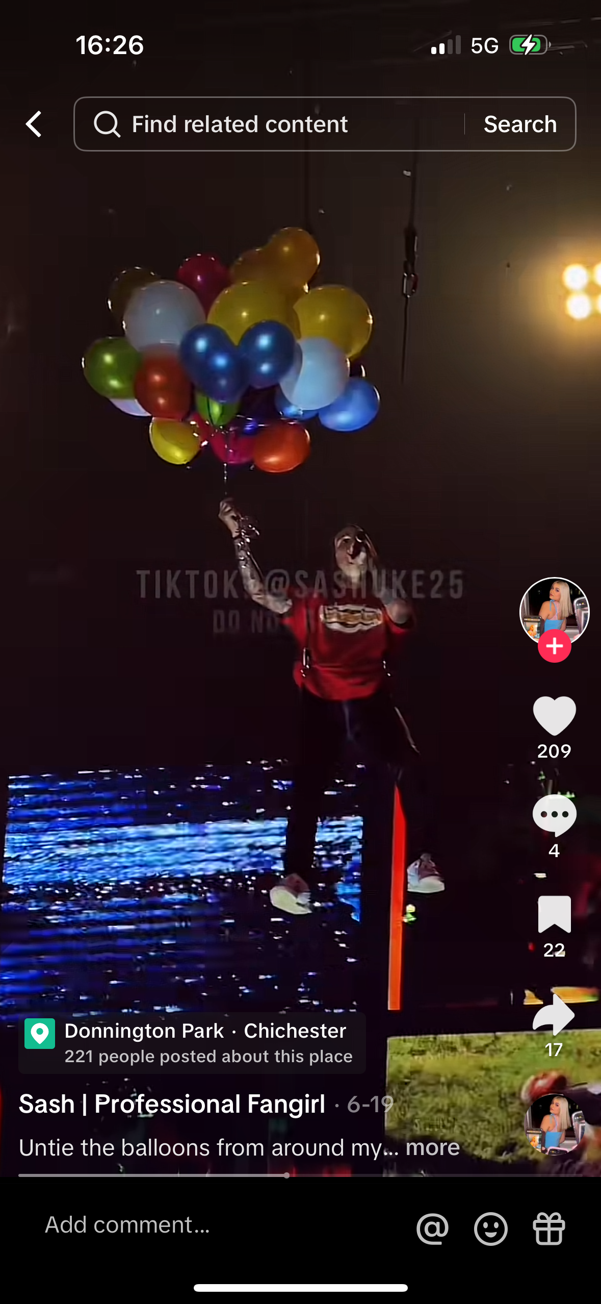 a screenshot from tiktok video of an influencer on a stage surrounded by balloons, a crowd watching. the influencer is holding a microphone and singing, the phone screen also shows the event location and the number of people that posted about it.