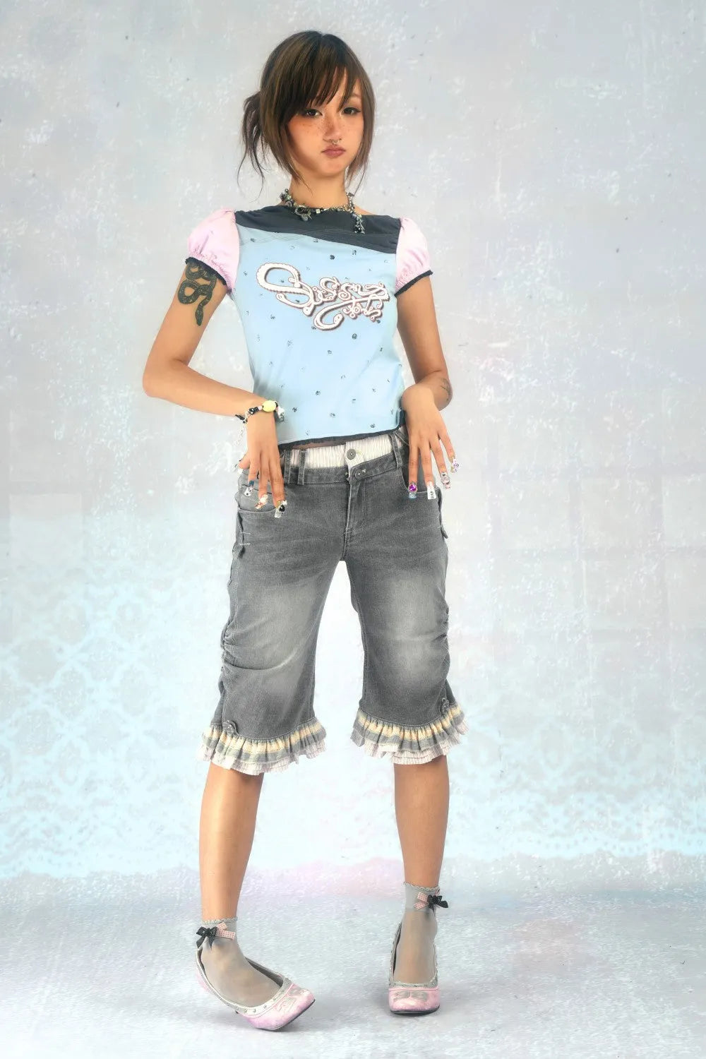 full shot of an asian girl posing in a studio against a light blue background. she's wearing a light blue and gray shortsleeved top with a graphic design, gray denim shorts with ruffle detailing at the hem, and pale pink flats. her hair is styled up, and she has a few accessories on.  the overall style is trendy and cute, with a pastel color palette.