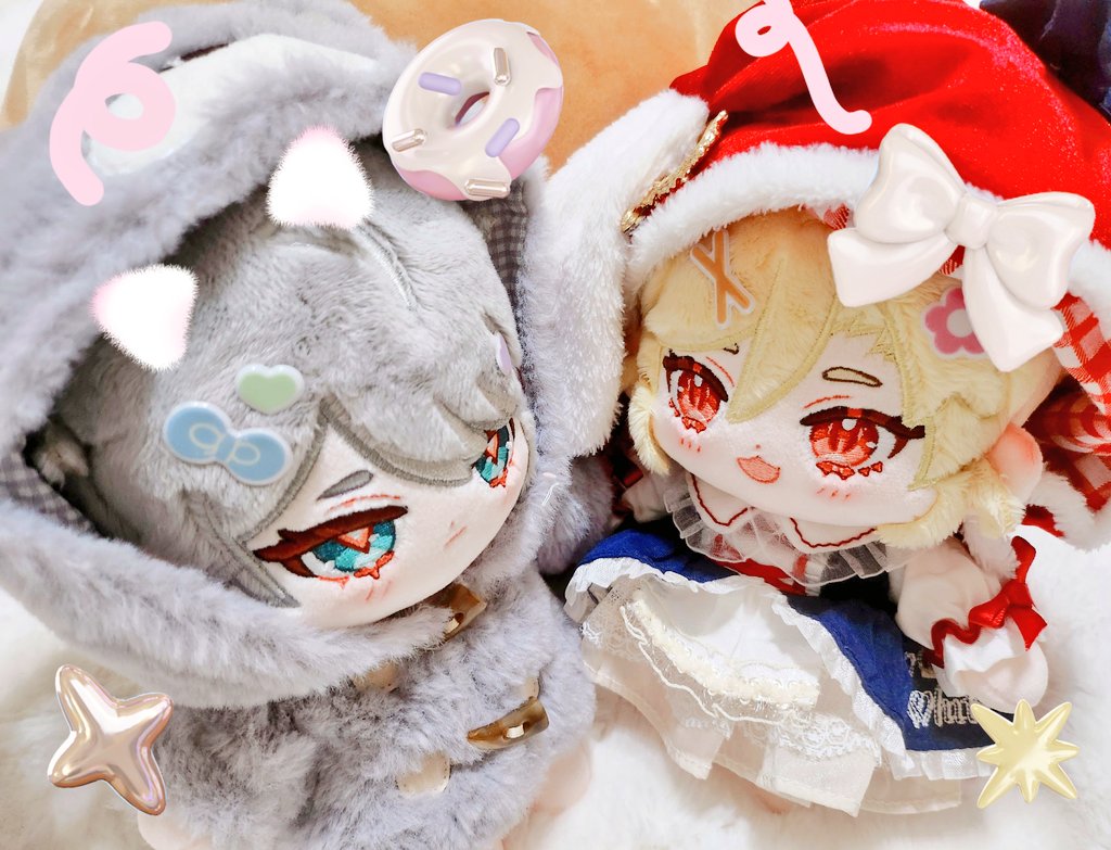 two adorable plush toys are sitting next to each other. the one on the left is a girl in a gray hooded coat and the one on the right is a girl in a red hat and blue and white dress. both of them have cute eyes and smiles. the background is white and fuzzy.  the gray plush toy is looking directly at the camera.