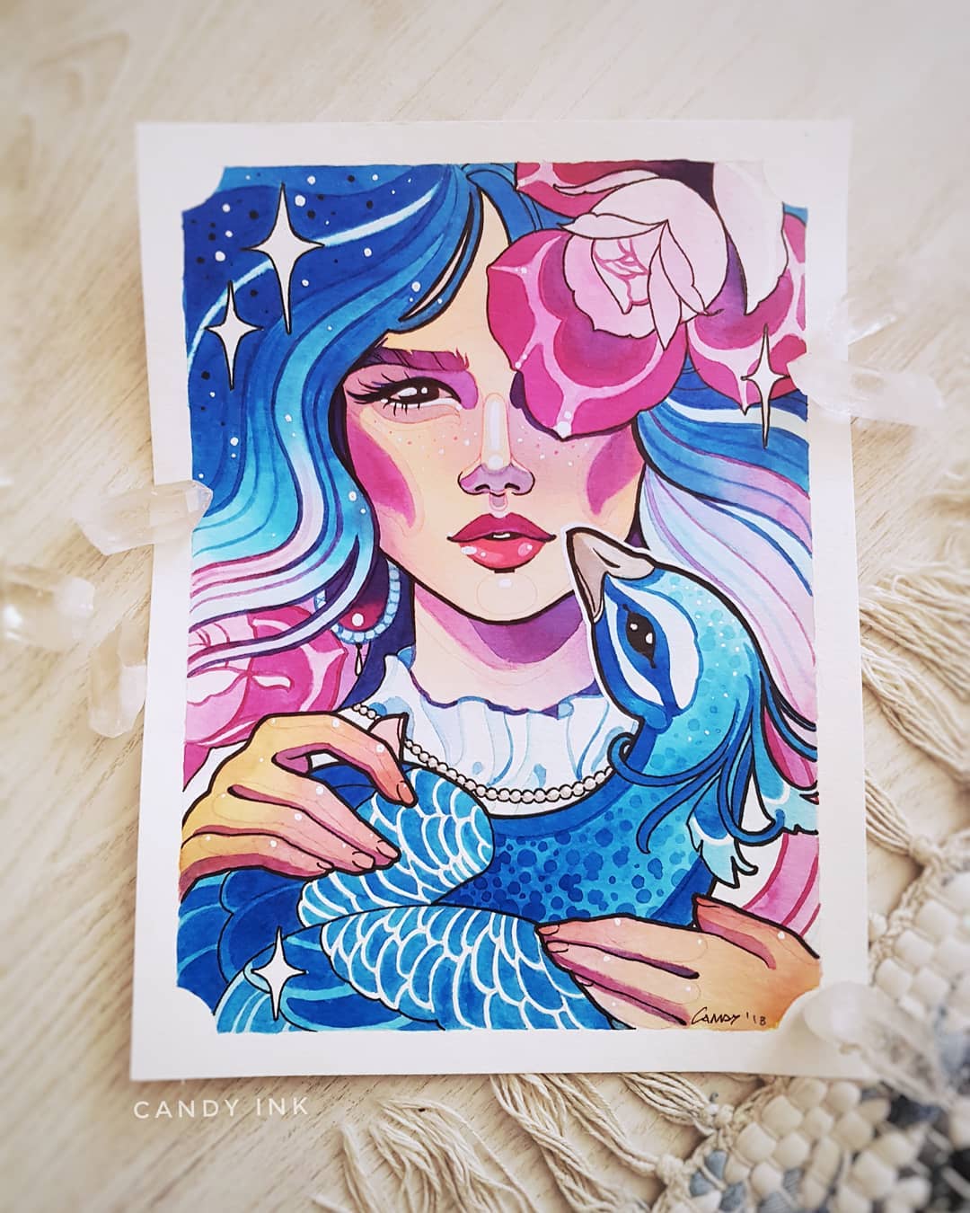 this is a watercolor illustration of a woman holding a peacock. the woman has blue and pink hair and is wearing a white dress. there are pink roses in her hair and around the peacock. the background is blue and white with stars.
