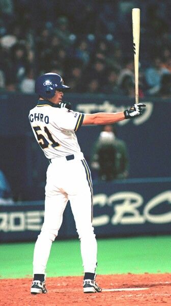 a japanese baseball player, wearing a white uniform with blue and yellow details and the number 51 on his back, is captured midswing at home plate. he is facing the left side of the image and is lit by stadium lights.  the background is blurred, showing the crowd and part of the stadium wall featuring a blue and yellow "cbc" logo. the image exudes energy and motion, capturing the intensity of the moment.