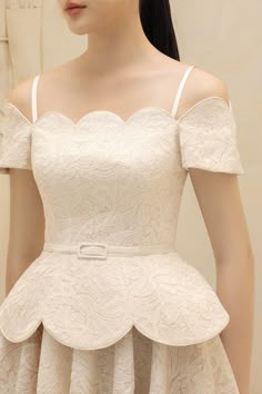 a beautiful woman in a white lace dress with a scalloped neckline, offtheshoulder straps, short sleeves, and a ruffled skirt. she is wearing a belt and has a floral pattern on the dress. the dress looks formal and elegant and could be perfect for a wedding or special occasion.