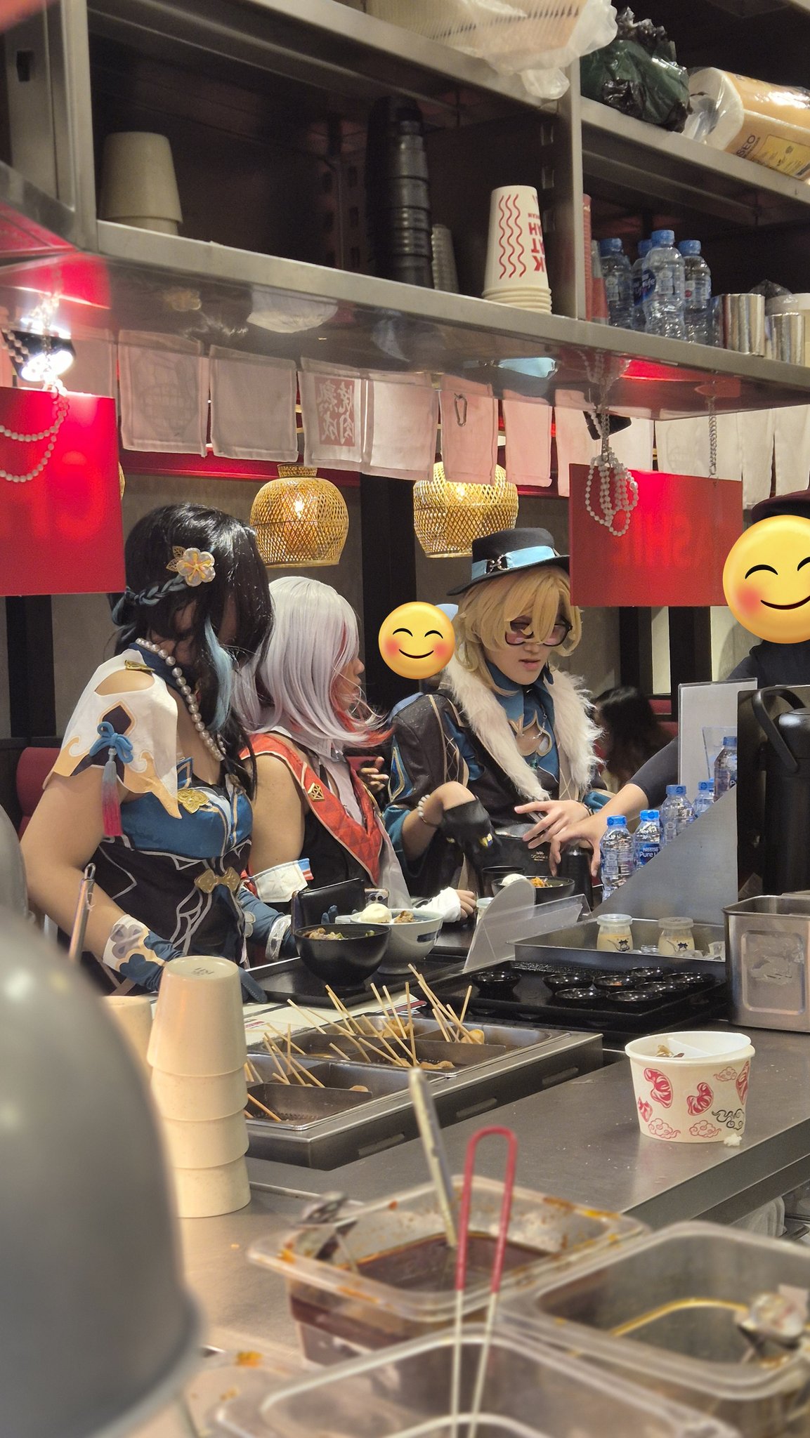 a photo of a food stall where a group of women are having a snack. the stall has a variety of food being prepared, including skewers of food and bowls of sauces. the women are wearing casual clothing and look like they are enjoying their snack. there are a lot of items on the counter that give the impression of a busy, fastpaced food stall.