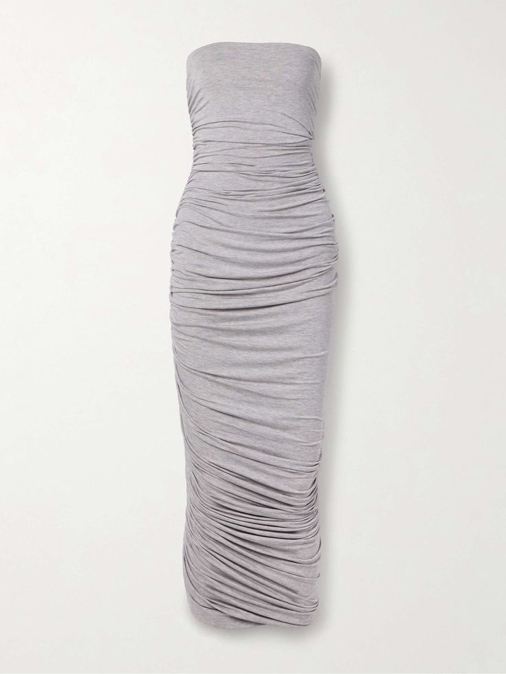 a grey strapless maxi dress with a ruched design, fitting closely to the body. the dress is sleeveless and made of a soft, stretchy material. it is perfect for a summer occasion, or a casual day out. the model is standing on a white background, with the dress looking very flattering and stylish.