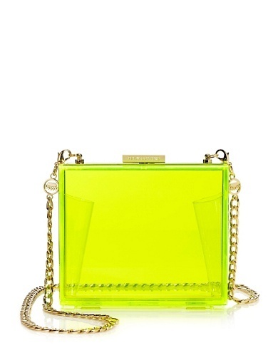 a bright neon yellow lucite clutch purse with a gold chain strap is showcased against a white backdrop. the clutch is rectangular, made of clear material, and has gold hardware including the chain and closure.