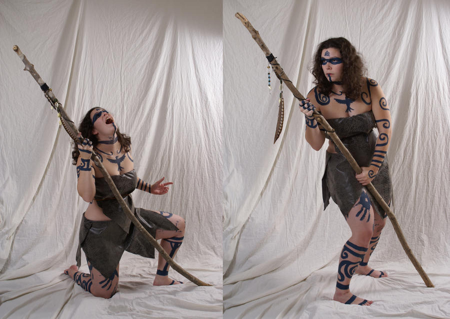 two images sidebyside show a woman in a fantasy costume posing with a staff. she is wearing body paint in tribal patterns and a leatherlike dress. in one image, she is kneeling and yelling, while in the other, she is standing and holding the staff. the background is a white sheet. she is barefoot in both poses.