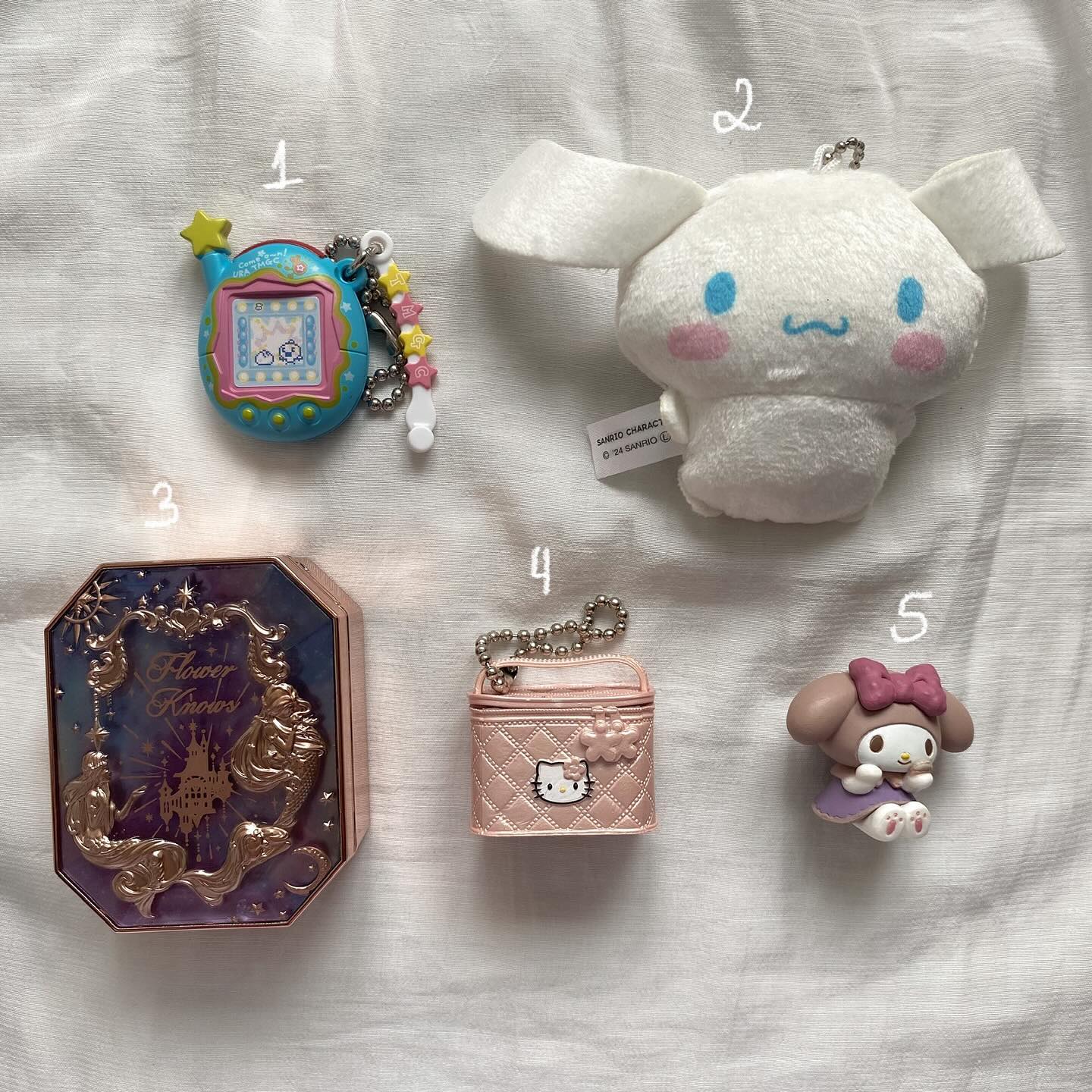 the image shows five items laid out on a white surface. they are labeled with numbers 1 through 5. item 1 is a blue tamagotchi with attached star keychains. item 2 is a small white cinnamoroll plush keychain. item 3 is a "flower knows" brand makeup compact case with ornate gold detailing on a purple background. item 4 is a light pink hello kitty airpod case with a zipper and a keychain. item 5 is a my melody figurine in a purple dress with a pink bow.