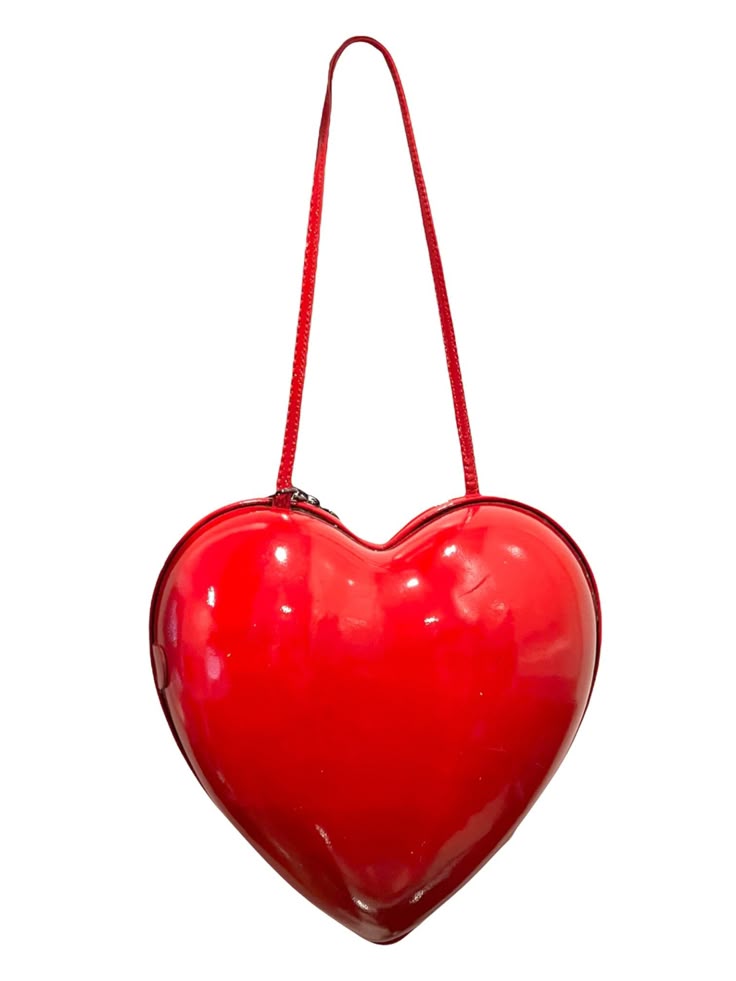 a glossy, red, heartshaped purse hangs from a red strap. it is presumably for valentine's day.