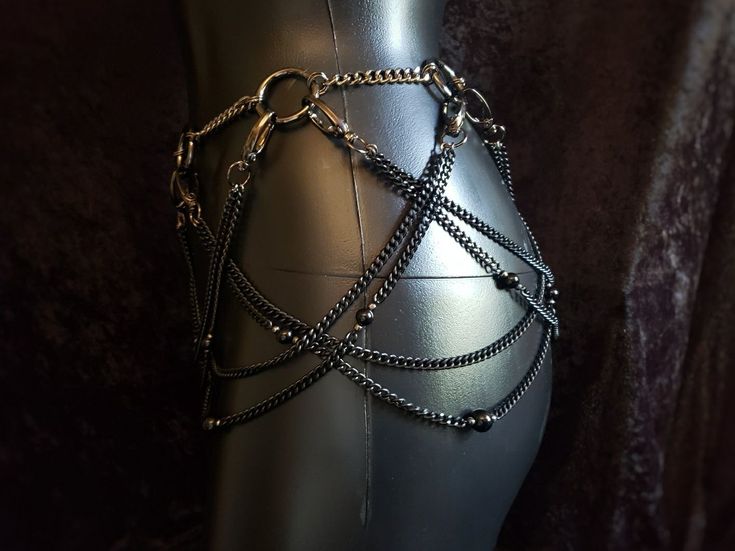 a closeup shot of a metallic body chain on a mannequin, featuring layered chains with bead accents.